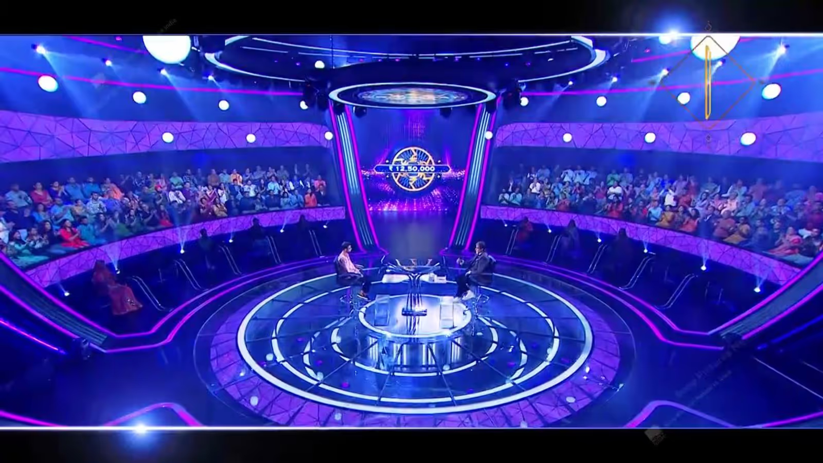 Silhouetted presenter under a single spotlight on a television quiz stage